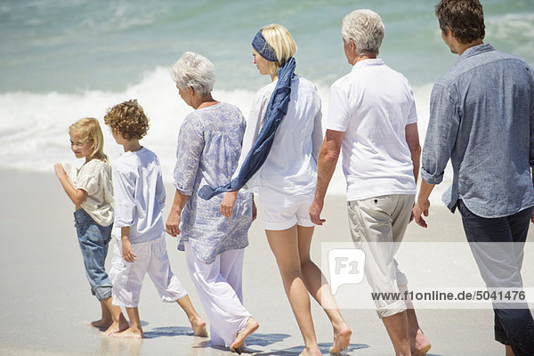 Mehrgenerationen-Familienwandern in einer Reihe am Strand