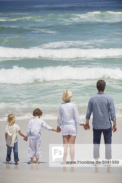 Paar mit zwei Kindern am Strand stehend