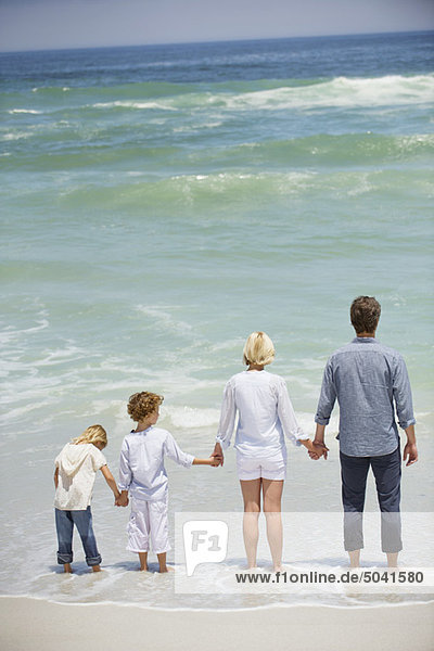 Familie mit zwei Kindern am Strand stehend