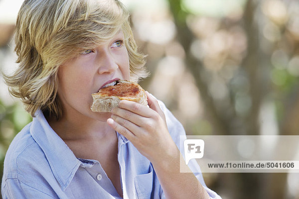 Kleiner Junge isst Brot im Freien