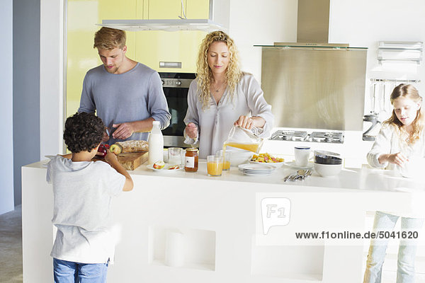 Paar mit ihren beiden Kindern beim Zubereiten von Essen in einer häuslichen Küche