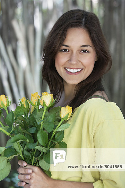 Porträt einer jungen Frau mit einem Strauß gelber Blumen