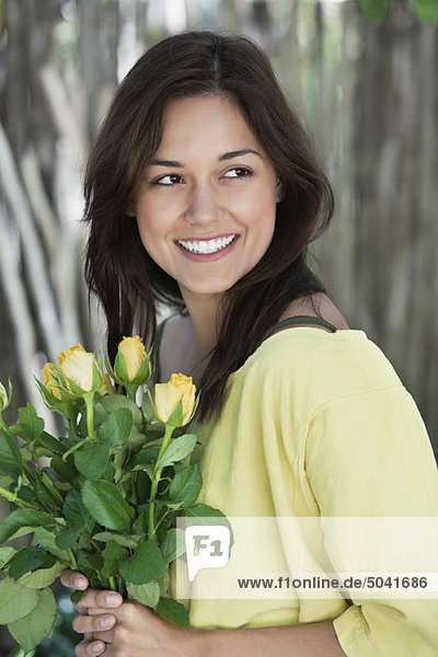 Junge Frau hält gelben Blumenstrauß und lächelt