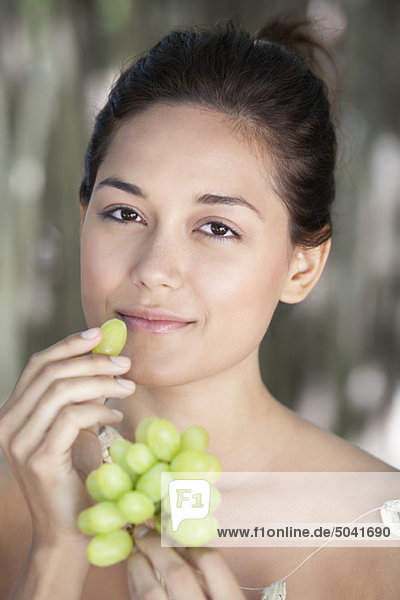 Portrait einer jungen Frau beim Traubenessen