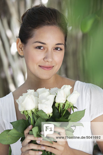 Portrait of a young woman holding bunch of white flowers