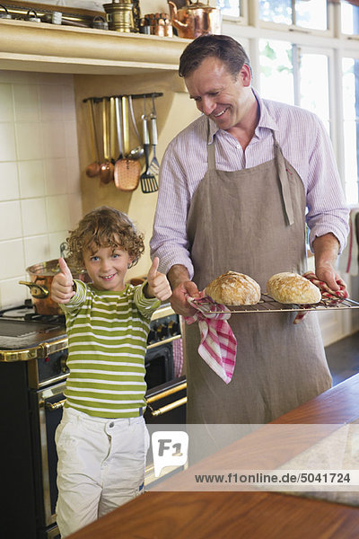 Kleiner Junge mit Daumen nach oben und Vater mit gebackenem Brot.
