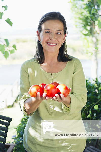Porträt einer älteren Frau mit Tomaten in der Hand