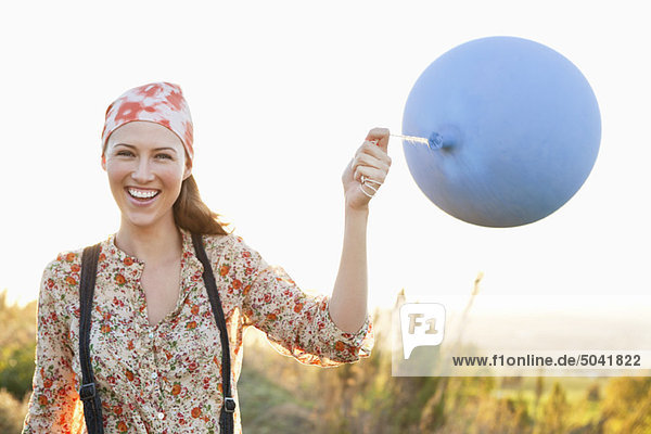 Schöne Frau spielt mit einem Ballon und lächelt.