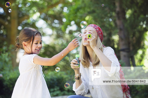 Mother and a little girl playing with bubble wand outdoors