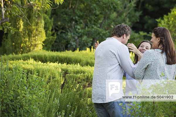 Ein reifes Paar  das seine Mutter im Garten umarmt.