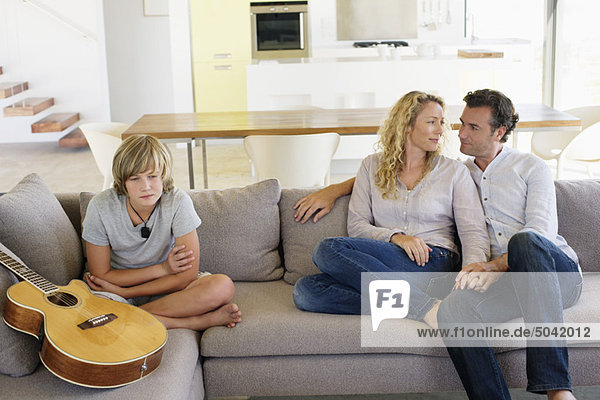 Teenager-Junge sitzend mit einer Gitarre auf einer Couch
