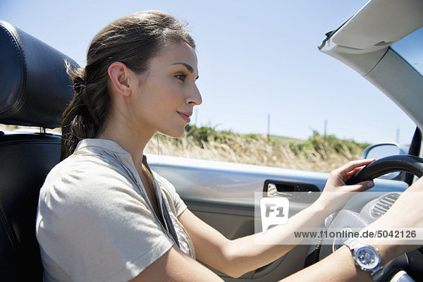 Young woman driving a convertible car