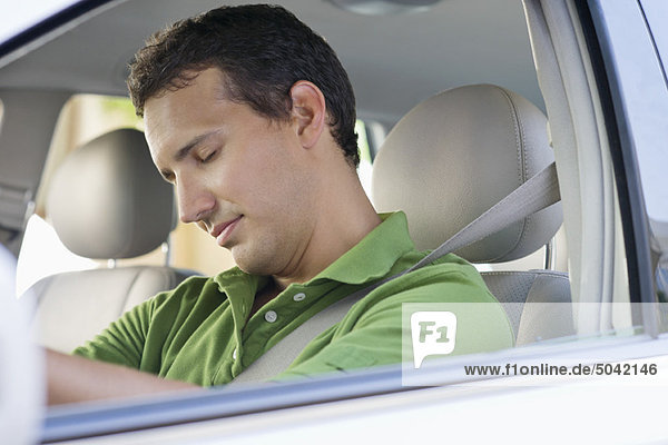Mittlerer Erwachsener Mann  der beim Autofahren schläft