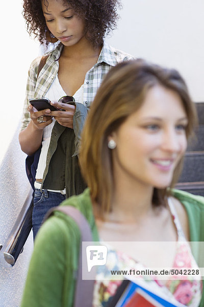 Nahaufnahme einer Studentin mit afroamerikanischer Frau über Handy im Hintergrund