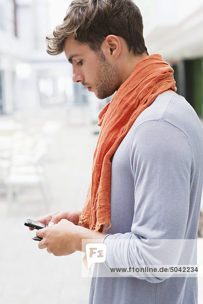 Seitenprofil eines jungen Mannes mit dem Handy