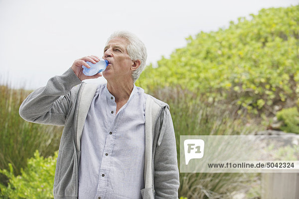 Durstiger älterer Mann trinkt Wasser