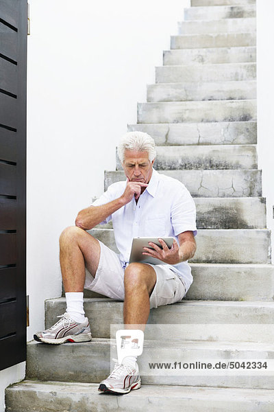Älterer Mann beim Betrachten des digitalen Tabletts