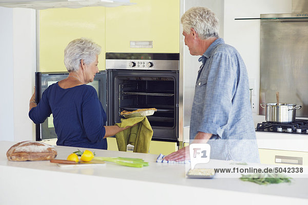 Seniorenpaar beim Backen im Ofen