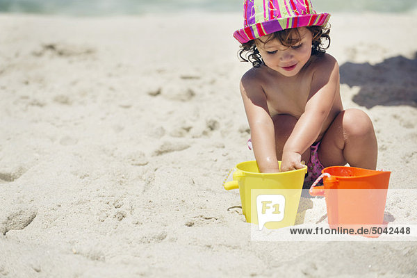Mädchen spielt mit Sand am Strand