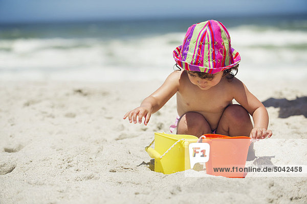 Mädchen spielt mit Sand am Strand