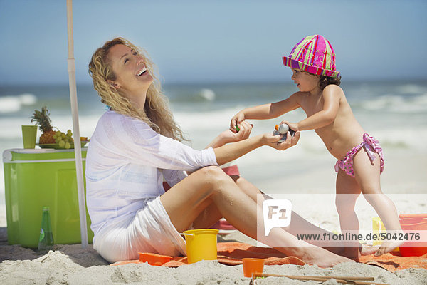 Frau spielt mit ihrer Tochter am Strand