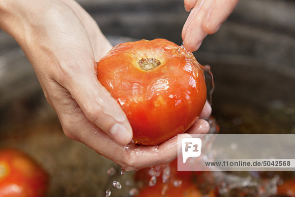 Nahaufnahme einer Frau beim Händewaschen von Tomaten