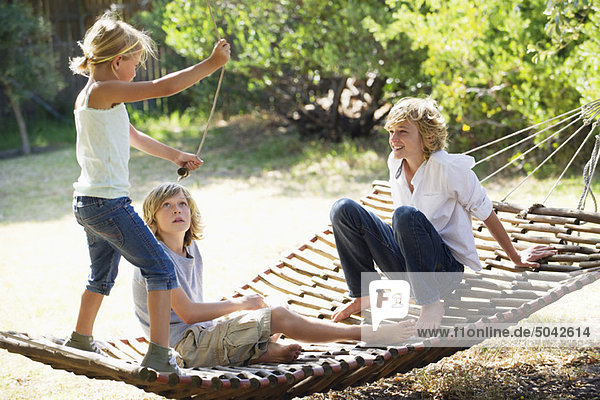 Smiling little siblings playing in hammock