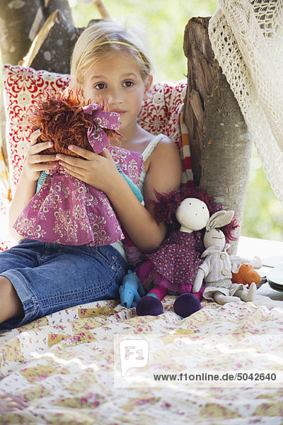 Contemplative little girl holding toys in tree house