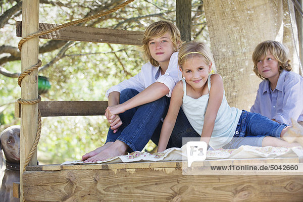 Portrait of children sitting in tree house