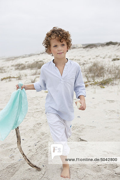 Boy holding flag and walking on beach