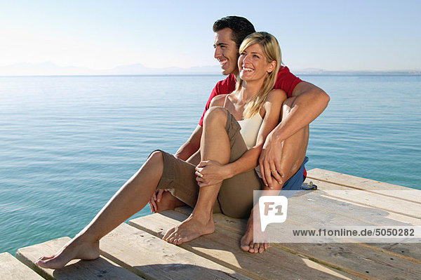 Glückliches Paar auf einem Steg am Meer