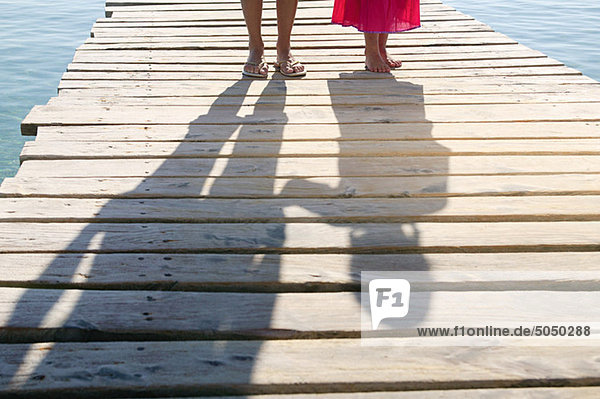 Shadows of child and adult on jetty
