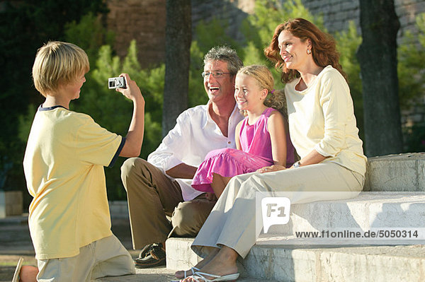 Boy taking photograph of family