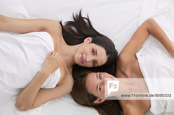 Zwei junge Frauen im Bett liegend  Draufsicht