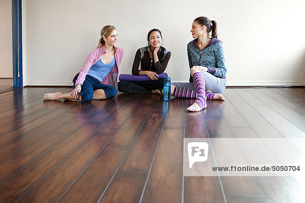 Three women sitting on gym floor