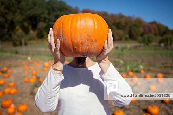 Person holding a pumpkin in front of face