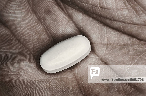 Einzelne Pille in Männerhand  Nahaufnahme