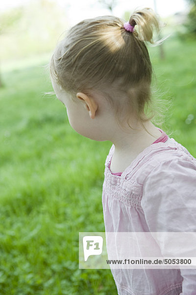 Kleinkind Mädchen im Freien  über die Schulter schauend