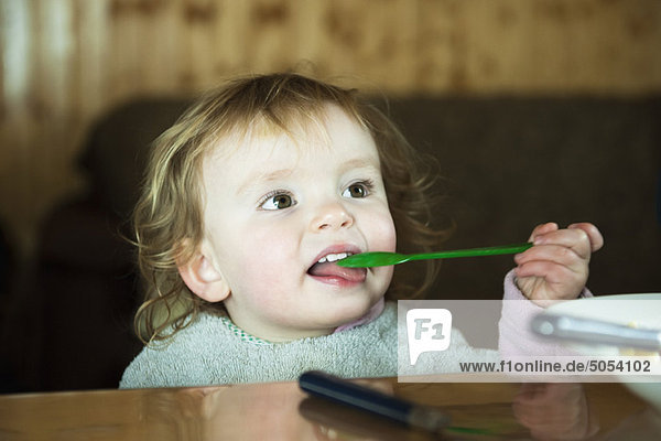 Kleinkind Mädchen füttert sich mit einem Löffel