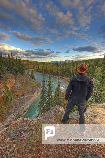 Hiker standing above the Lapie River near Ross River at sunset  Yukon.