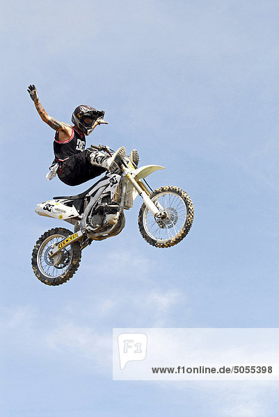 A motocross stunt rider airborn in a jump with his motor bike at a show in Alberta  Canada