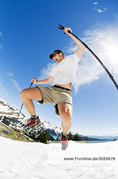 A hiker bounds down a summer snowfield above Garibaldi Lake in Garibaldi Provincial Park  BC.