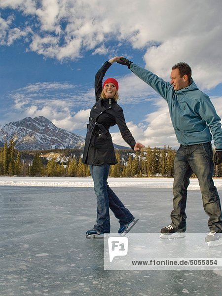 Couple ice skating on frozen Mildred Lake at The Fairmont Jasper Park Lodge near Jasper  Alberta  Canada.