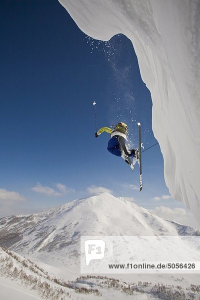 Ein Skifahrer Flys Weg ein Gesims mit Mt Annupuri im Hintergrund  Niseko Backcountry  Hokkaido  Japan