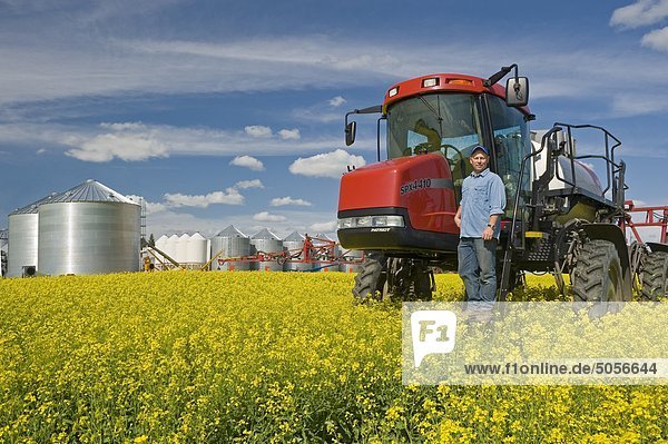 Landwirt in Blüte Bühne Raps Feld mit hoher Freiraum Sprayer, in der