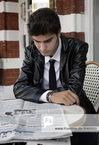 Young man reading newspaper in a cafe