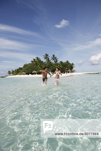 Couple at sea running in shallow water