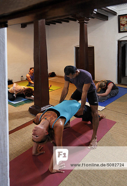 Mann assisting Frau macht yoga