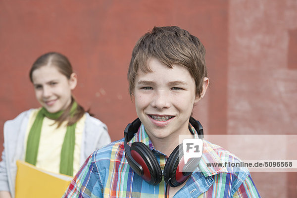 Lächelnder Junge mit Kopfhörer und Mädchen mit Mappe