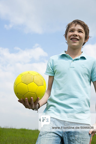 Junge hält einen Fußball im Freien